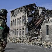 A Ukrainian soldiers looks at the heavily damaged building after Russian attacks