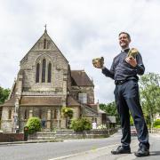 Revd Mike Trotman holding the cracked stone outside St Peter's Church, Parkstone.
