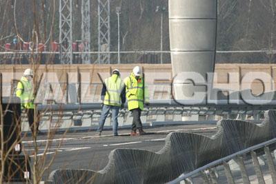 Building contractors inspect the road surface on the Twin Sails bridge in Poole with representatives from Poole Borough Council after some of the the tarmac has fallen off .