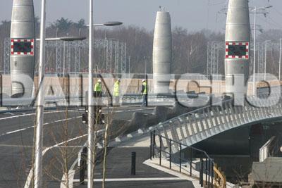 Building contractors inspect the road surface on the Twin Sails bridge in Poole with representatives from Poole Borough Council after some of the the tarmac has fallen off .