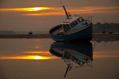 Fishing boats in Poole Harbour during low tide at sunset. Picture by Andrew Ward.