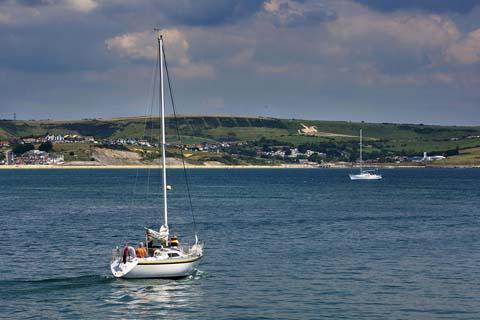 A typical summer scene looking out across Weymouth Bay with para gliders flying over the White Horse and yachts on the water, by Andy Harris 