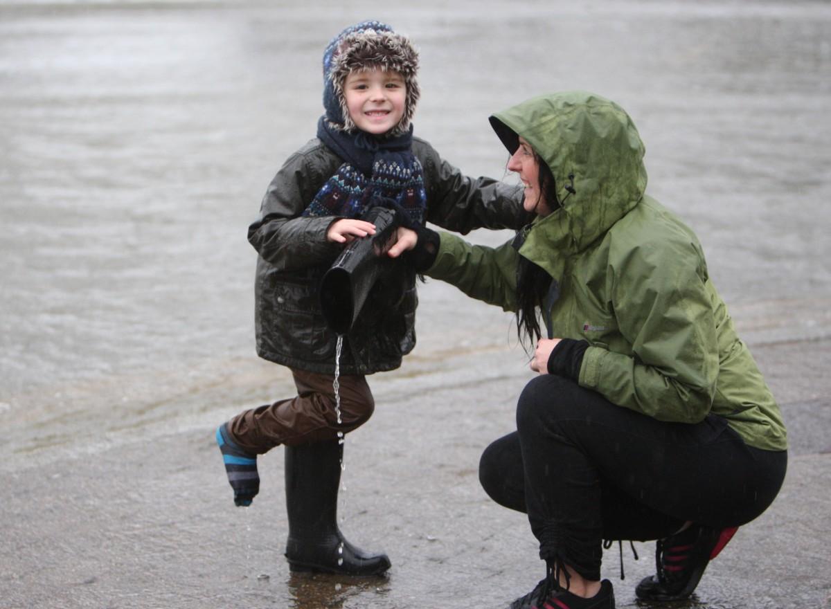 Heavy rain and strong winds cause flooding and high tides across Dorset. Jack Olley, 5,  gets some help from his mum to empty his wellies at Christchurch Quay
