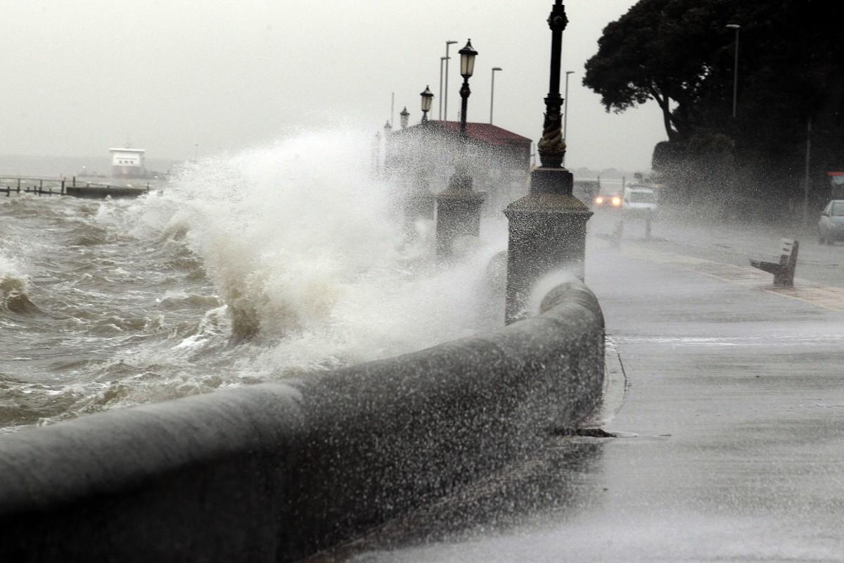 Waves crash over the sea defense wall on Sandbanks Road as Dorset gets battered by strong winds and high tides.