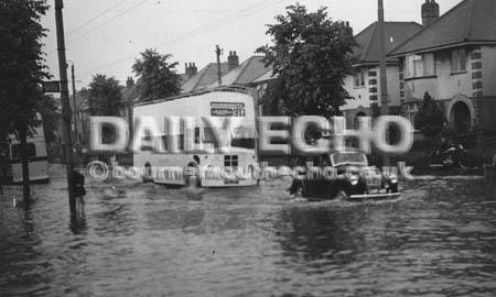 Vehicles gingerly negotiate flood waters at Iford after storms hit the area in July 1955.