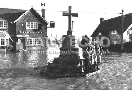 These boys keep themselves dry on the steps of  the cross at Shapwick when the village is flooded in the 1979 storms.