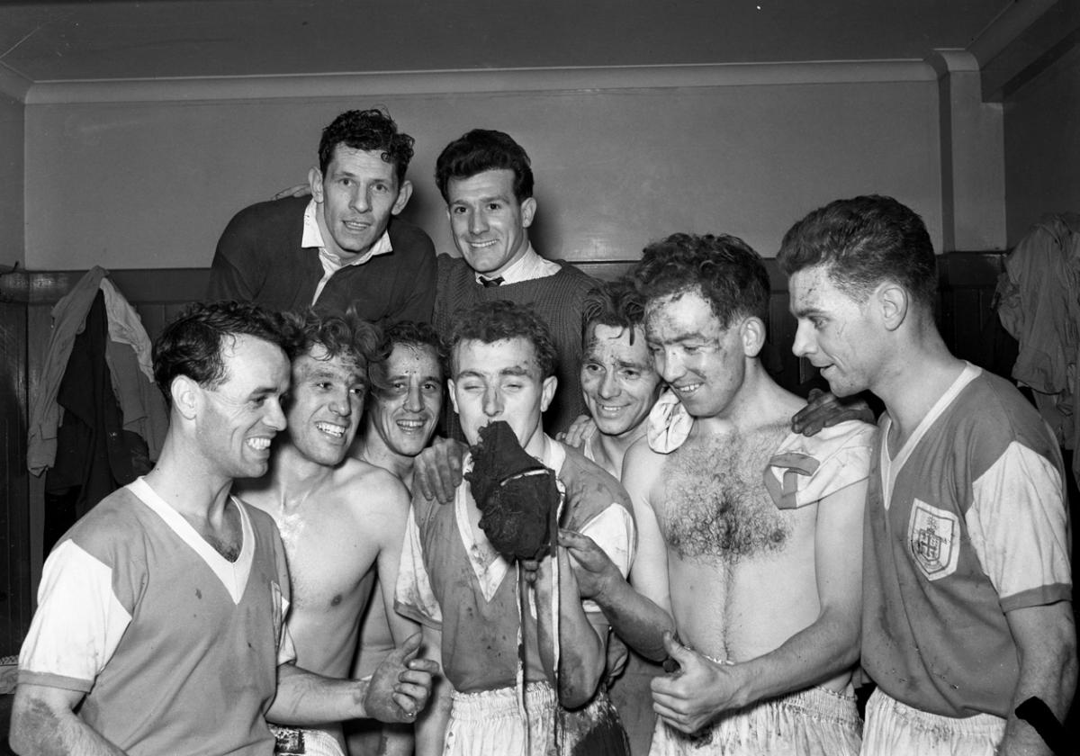 Reg Cutler kisses the boot that put Wolves out of the F.A. Cup and Boscombe into the round five.  Other in the dressing room picture,  left to right,  Nelson Stiffle, Joe Brown, Stan Newsham, Lew Clayton, Oliver Norris and Arnold Woollard.  Wolverhampton 