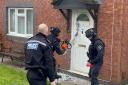 ACTION: Police with a chainsaw hack their way through a door in Canterbury Road in Ronkswood, Worcester