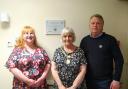 Sue Wiffen, Cllr Anne Filer and Iain Slack, stand next to the newly received EMBRACE Dementia Accreditation at Red Admiral View.