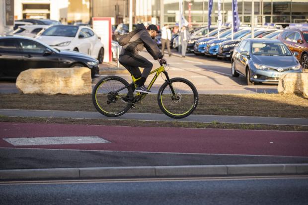 Bournemouth Echo: A cyclist travelling on the pavement next to the new cycle lane in Wallisdown Road. Picture: BNPS