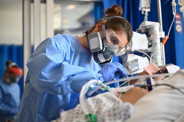Bournemouth Echo: Clinical staff wear personal protective equipment (PPE) while caring for a patient in the intensive care unit at Royal Papworth Hospital, Cambridge.  PA photo.  Picture date: Tuesday May 5, 2020. NHS employees have increased levels of PPE at higher risk