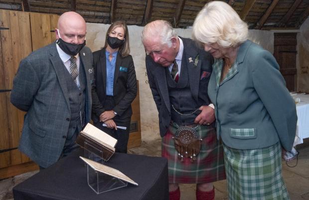 Bournemouth Echo: The Prince of Wales and the Duchess of Cornwall, known as the Duke and Duchess of Rothesay when in Scotland, take a look at the original manuscript of Auld Lang Syne during a visit to Robert Burns' Cottage in Alloway, South Ayrshire. Photo via PA/Jane Barlow.