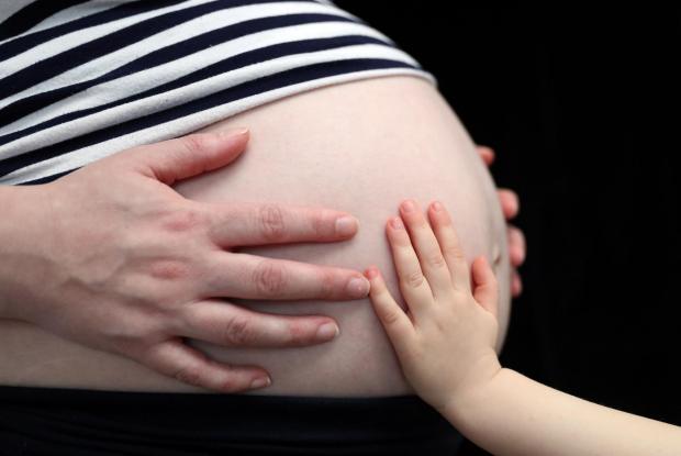 Bournemouth Echo: A child touching a pregnant woman's stomach. Credit: PA
