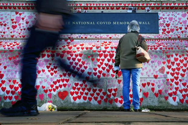 A woman pauses to look at dedications written on the National Covid Memorial Wall, in Westminster, London. Picture date: Thursday January 13, 2022.