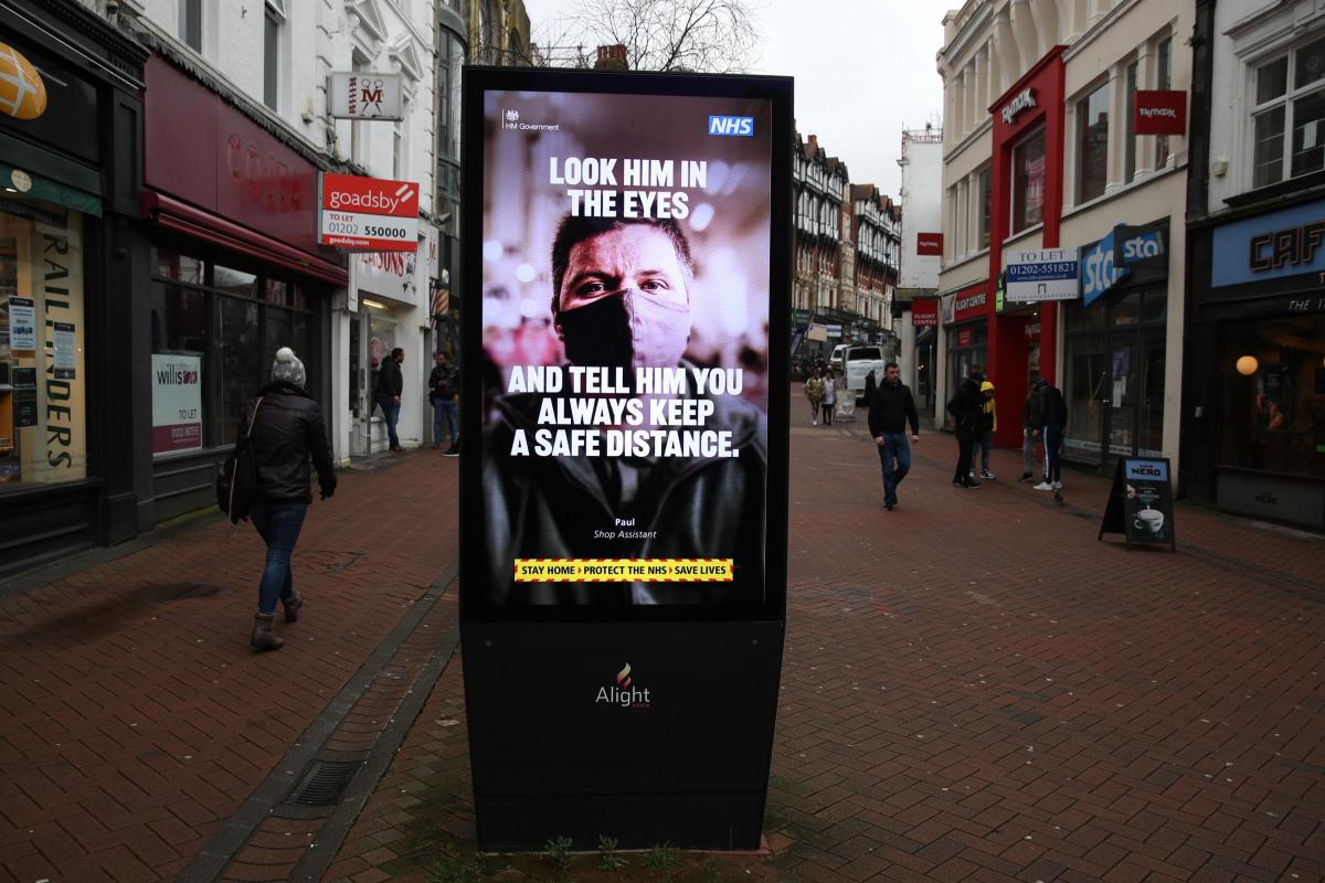People make their way past a government coronavirus sign on Old Christchurch road in Bournemouth, during England's third national lockdown