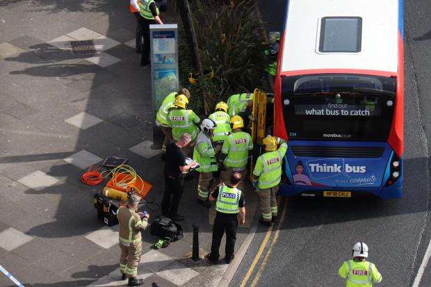 Bournemouth Echo: Emergency services work to free elderly man trapped under a bus on George Roundabout, Poole
