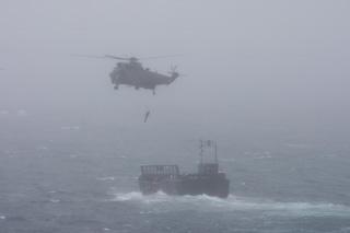  Bournemouth Air Festival Day Three - Day on RFA Largs Bay  -  With visibility severely reduced ,A Sea King helicopter winches  a Royal Marine from a landing craft in the gloom.