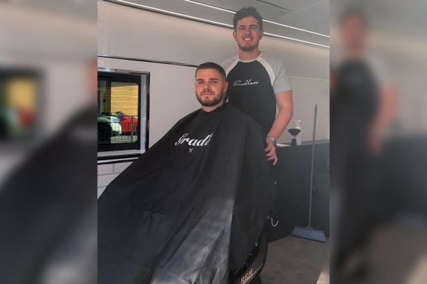 Bournemouth Echo: Hairdresser Niall Coles with a customer inside the Grade 92 Barbering mobile van