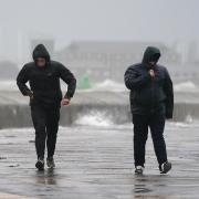 People brave the weather as they make their way along the sea front in Southsea as Storm Barra hit the UK and Ireland. Credit: PA