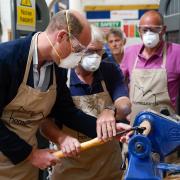 The Prince of Wales uses a lathe during a visit to Faithworks Carpentry Workshop