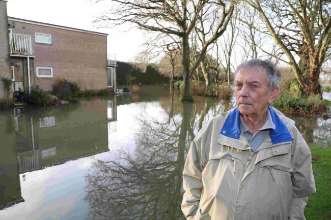 WATER RISES: Conifer Close resident Eric Matthews stands in the flood waters that now surround his block of flats