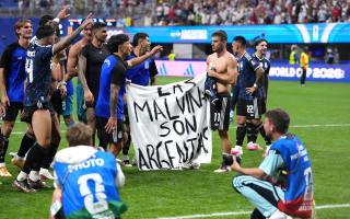 Argentina players hold up a banner with the words 'Las Malvinas son Argentinas' which translates to 'The Malvinas are Argentine